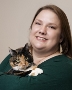 Bio photo of Karen Green smiling in a dark grren shirt holding a tan, black and white cat